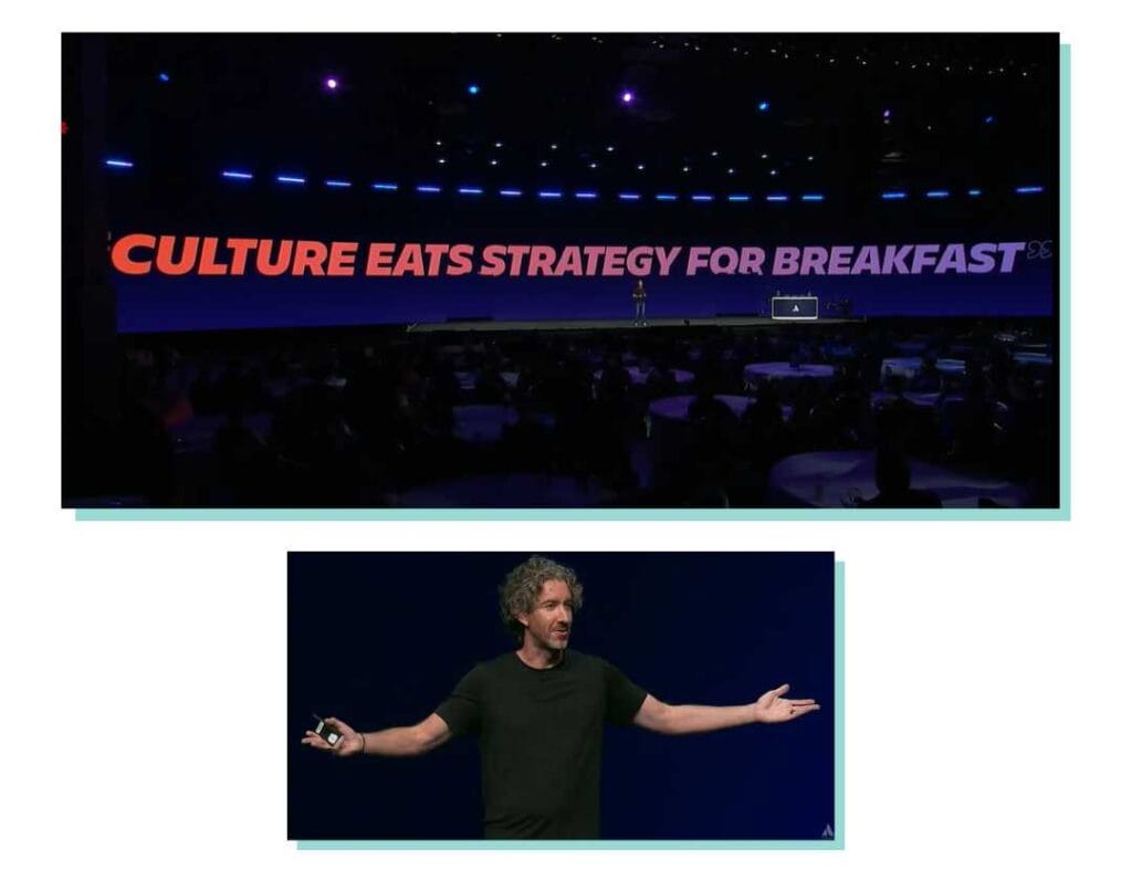 The co-CEO of Atlassian uses a quote to set the theme of his keynote. The quote used, --"Culture eats strategy for breakfast," by Peter Drucker -- is displayed on a large screen.